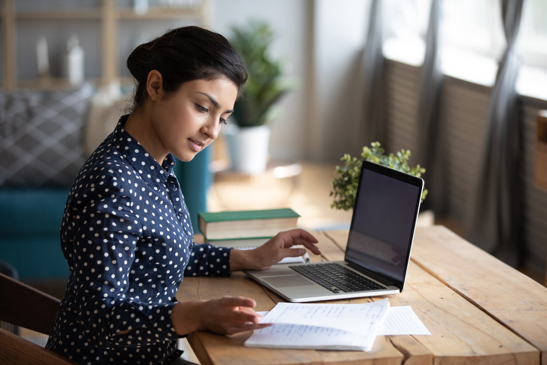 Millennial Indian girl study at laptop making notes